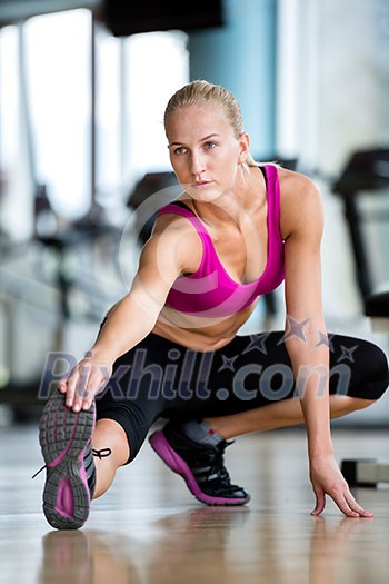 Cute young woman stretching and warming up for her training at a gym Cute young woman stretching and warming up for her training at a gym