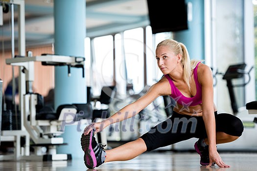 Cute young woman stretching and warming up for her training at a gym Cute young woman stretching and warming up for her training at a gym