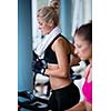 Beautiful group of young women friends  exercising on a treadmill at the bright modern gym