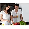 happy young couple have fun in modern kitchen indoor while preparing fresh fruits and vegetables food salad