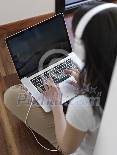 beautiful young woman relax and work on laptop computer modern home office while listening musin on white headphones beautiful young woman relax and work on laptop computer modern home office while listening musin on white headphones