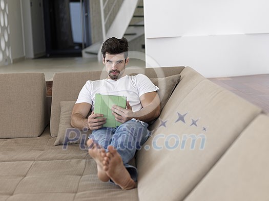 Handsome relaxed young businessman working from home on tablet computer Handsome relaxed young businessman working from home on tablet computer