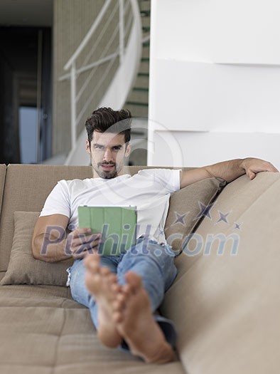 Handsome relaxed young businessman working from home on tablet computer Handsome relaxed young businessman working from home on tablet computer