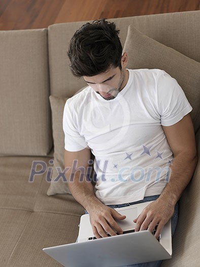 Man Relaxing On Sofa With Laptop In New Home Man Relaxing On Sofa With Laptop In New Home
