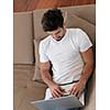 Man Relaxing On Sofa With Laptop In New Home