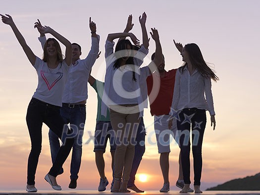 group of happy young people dancing and have fun on party in modern home bacony with sunset and ocean in background group of happy young people dancing and have fun on party in modern home bacony with sunset and ocean in background