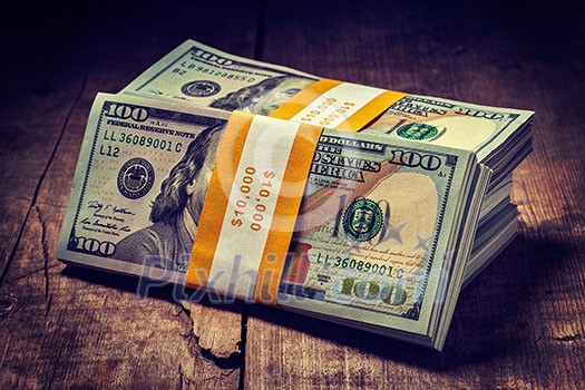 Creative business finance making money concept. Vintage retro effect filtered hipster style image of stacks of new 100 US dollars 2013 edition banknotes bills bundles isolated on wooden background Creative business finance making money concept. Vintage retro effect filtered hipster style image of stacks of new 100 US dollars 2013 edition banknotes bills bundles isolated on wooden background