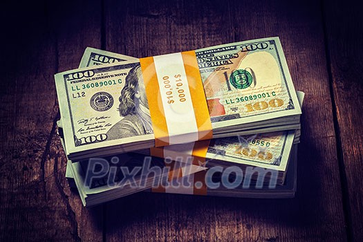 Creative business finance making money concept. Vintage retro effect filtered hipster style image of stacks of new 100 US dollars 2013 edition banknotes bills bundles isolated on wooden background Creative business finance making money concept. Vintage retro effect filtered hipster style image of stacks of new 100 US dollars 2013 edition banknotes bills bundles isolated on wooden background