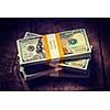 Creative business finance making money concept. Vintage retro effect filtered hipster style image of stacks of new 100 US dollars 2013 edition banknotes bills bundles isolated on wooden background