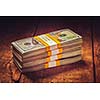Creative business finance making money concept. Vintage retro effect filtered hipster style image of stacks of new 100 US dollars 2013 edition banknotes (bills) bundles isolated on wooden background