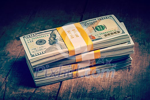 Creative business finance making money concept. Vintage retro effect filtered hipster style image of stacks of new 100 US dollars 2013 edition banknotes bills bundles isolated on wooden background Creative business finance making money concept. Vintage retro effect filtered hipster style image of stacks of new 100 US dollars 2013 edition banknotes bills bundles isolated on wooden background