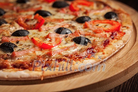 Ham pizza with capsicum and olives on wooden board on table close up Ham pizza with capsicum and olives on wooden board on table close up