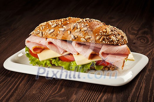 Ham sandwich with lettuce, cheese, tomato on plate on wooden table Ham sandwich with lettuce, cheese, tomato on plate on wooden table