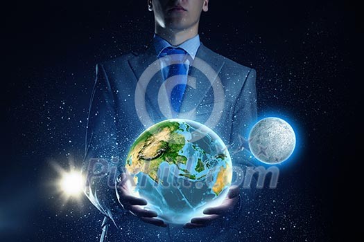 Young businessman holding Earth planet in palm. Elements of this image are furnished by NASA Young businessman holding Earth planet in palm. Elements of this image are furnished by NASA