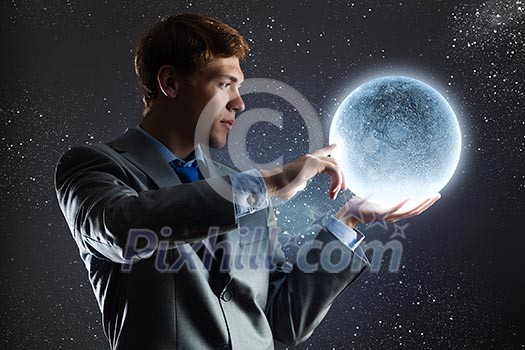 Young man in suit holding moon in palm Young man in suit holding moon in palm