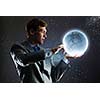 Young man in suit holding moon in palm