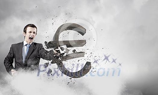 Businessman breaking stone euro symbol with karate punch Businessman breaking stone euro symbol with karate punch