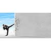 Businessman breaking stone wall with karate kick