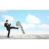 Angry businessman crashing stone key with kick