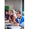 Handsome college student sitting in a classroom full of students during class  (color toned image; shallow DOF)