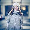 Autumn/winter portrait: young woman dressed in a warm woolen cardigan posing outside in a city park