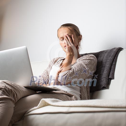 Very tired young woman, burning the midnigh oil - working late at night on her laptop computer, at home, sitting on sofa, rubbing her tired eyes, trying to stay focused Very tired young woman, burning the midnigh oil - working late at night on her laptop computer, at home, sitting on sofa, rubbing her tired eyes, trying to stay focused