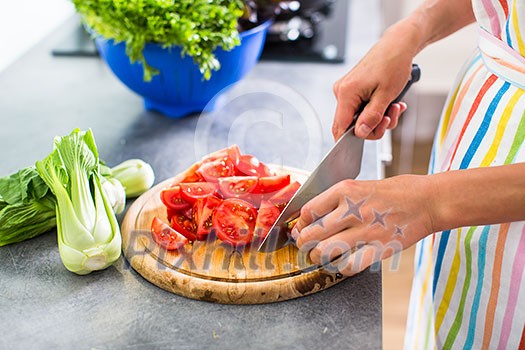 Young woman cutting vegetables in her modern kitchen - fixing a salad Young woman cutting vegetables in her modern kitchen - fixing a salad
