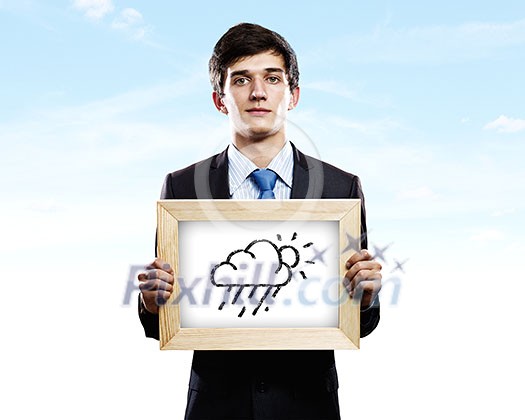 Young businessman holding frame with weather drawings Young businessman holding frame with weather drawings