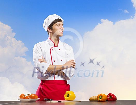 Young cheerful cook and ingredients flying in air Young cheerful cook and ingredients flying in air