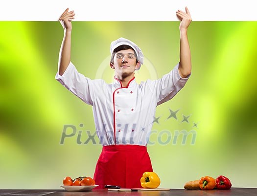 Young handsome cook holding white blank banner Young handsome cook holding white blank banner
