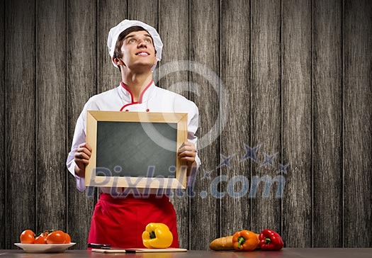 Handsome cook holding blank chalk board. Place for text Handsome cook holding blank chalk board. Place for text