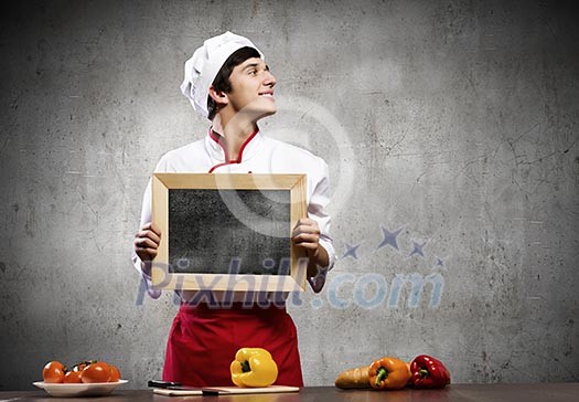 Handsome cook holding blank chalk board. Place for text Handsome cook holding blank chalk board. Place for text