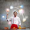 Young cheerful cook and ingredients flying in air