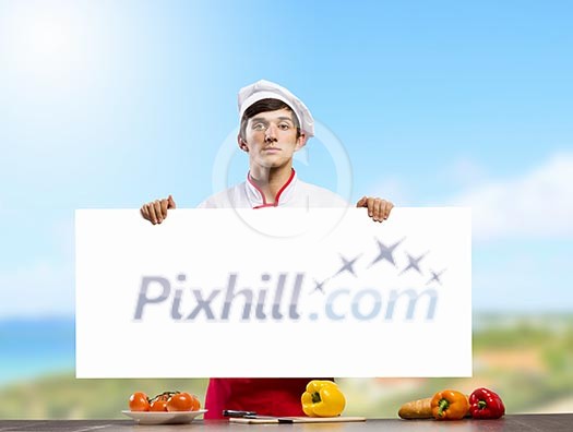 Young handsome cook holding white blank banner