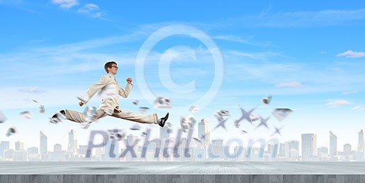 Young cheerful businessman in jump against city background Young cheerful businessman in jump against city background