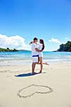 happy young couple have fun and relax  on the summer with heart drawing on beach sand
