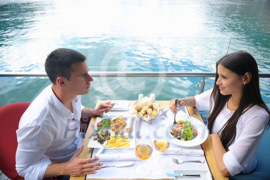 happy young couple having lanch at beautiful restaurant on by the sea on beach happy young couple having lanch at beautiful restaurant on by the sea on beach