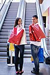 happy young couple with bags in shopping centre mall