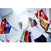 happy young couple with bags in shopping centre mall