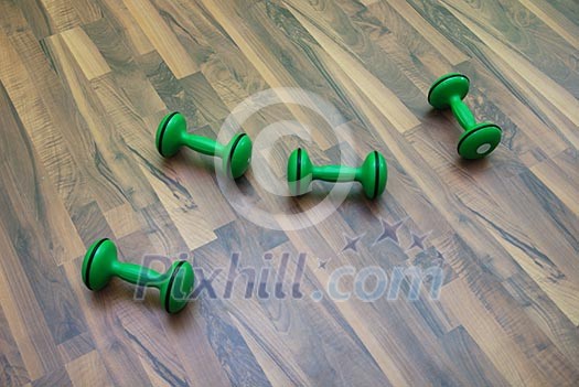 green dumbbells on patquet floor green dumbbells on patquet floor