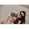 beautiful happy young  woman in black dress with cute small dog puppy have fun on street