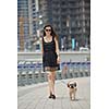 beautiful happy young  woman in black dress with cute small dog puppy have fun on street