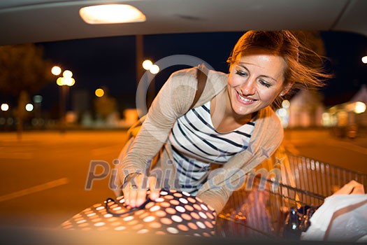 Beautiful young woman shopping in a grocery store/supermarket (color toned image), putting the groceries into her car in the parking lot, looking around Beautiful young woman shopping in a grocery store/supermarket (color toned image), putting the groceries into her car in the parking lot, looking around