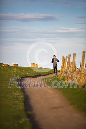 Young woman on her evening jog along the seacoast Young woman on her evening jog along the seacoast