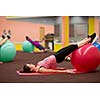 Group people in a pilates class at the gym - young woman with gymball at fitness training (shallow DOF, color toned image)