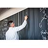 Senior chemistry professor writing on the board while having a chalk and blackboard lecture (shallow DOF; color toned image)