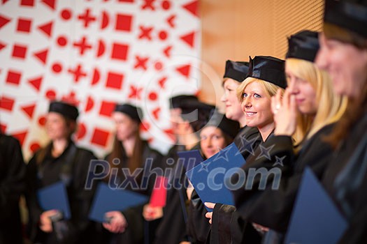 Pretty female college graduate at graduation with classmates, holding their degres. looking happy about their accomplishment Pretty female college graduate at graduation with classmates, holding their degres. looking happy about their accomplishment
