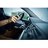 Male driver's hands driving a car on a highway (color toned image; shallow DOF)