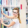 Pretty, female college student in a library, looking for a book (shallow DOF; color toned image)