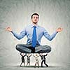 Young businessman sitting in lotus pose and supported by colleagues